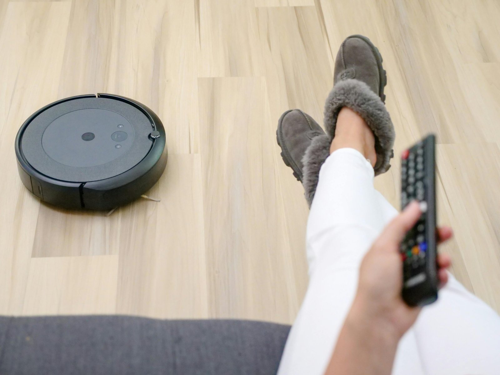 Melhor aspirador de pó robô navegando em sala com piso de madeira e sofá cinza
